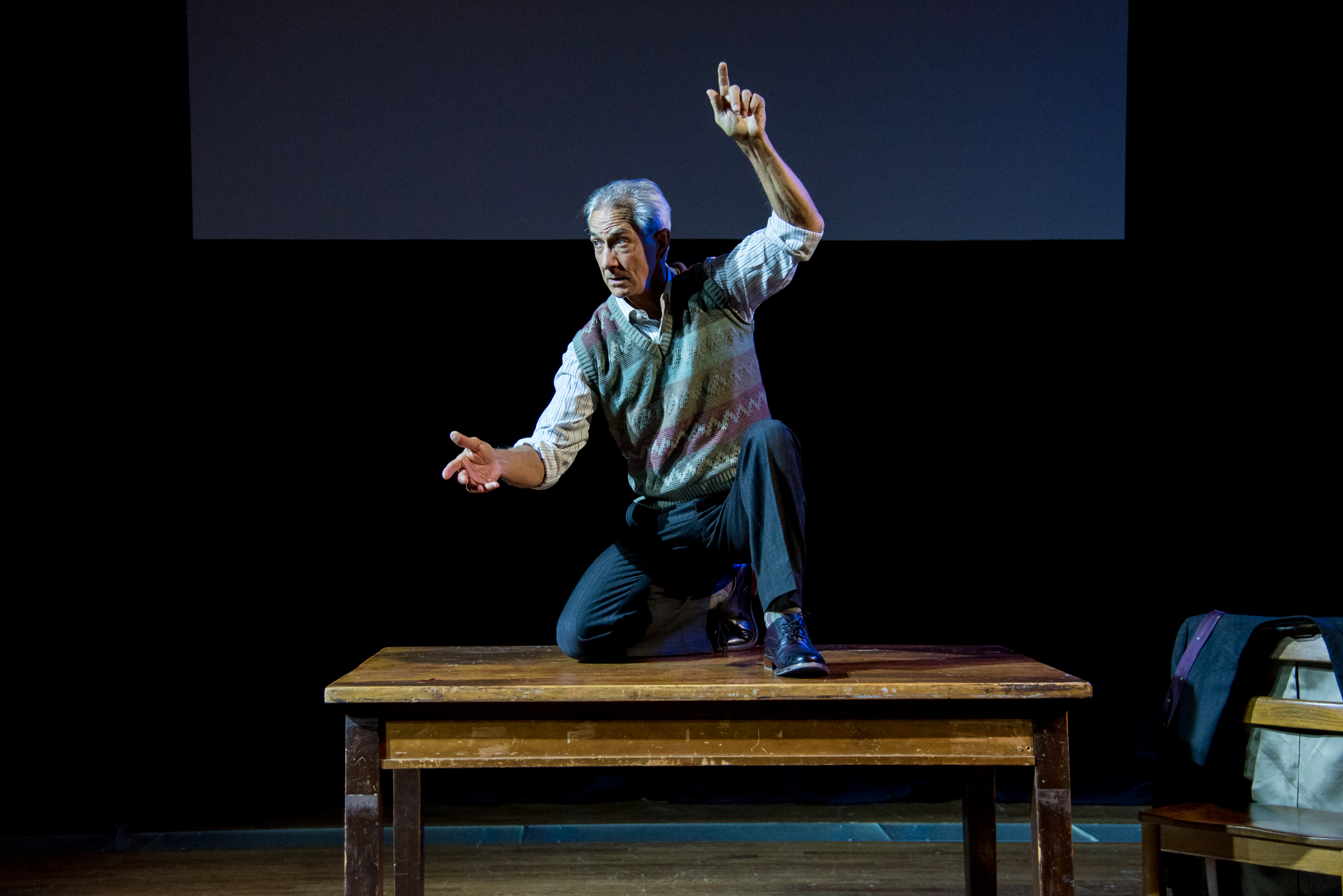 David Strathairn on stage on a table