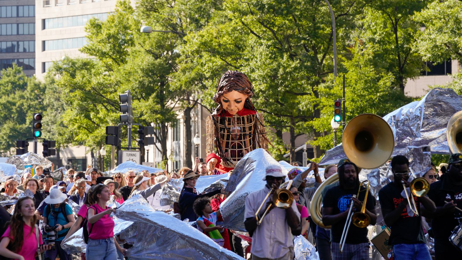 As Amal began her journey down Pennsylvania Avenue to the rhythm of the Dupont Brass band, the crowd unfurled a shimmering sea of emergency blankets, forming a symbolic ocean that represented the perilous journeys refugees and displaced children undertake in search of safety.