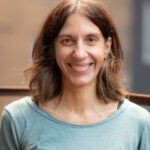 Woman with shoulder length brown hair and a blue shirt smiles at the camera